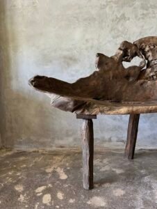 Banc en teck ancien avec design tripode et dossier ajouré, pièce artisanale unique.