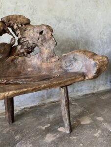 Banc en teck ancien avec design tripode et dossier ajouré, pièce artisanale unique.