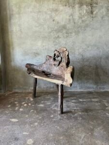 Banc en teck ancien avec design tripode et dossier ajouré, pièce artisanale unique.