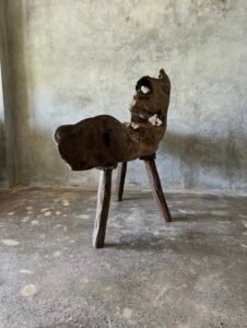 Banc en teck ancien avec design tripode et dossier ajouré, pièce artisanale unique.