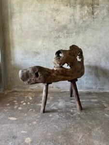 Banc en teck ancien avec design tripode et dossier ajouré, pièce artisanale unique.