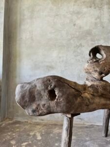 Banc en teck ancien avec design tripode et dossier ajouré, pièce artisanale unique.