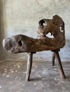 Banc en teck ancien avec design tripode et dossier ajouré, pièce artisanale unique.