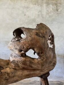 Banc en teck ancien avec design tripode et dossier ajouré, pièce artisanale unique.