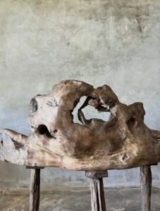 Banc en teck ancien avec design tripode et dossier ajouré, pièce artisanale unique.