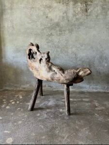 Banc en teck ancien avec design tripode et dossier ajouré, pièce artisanale unique.