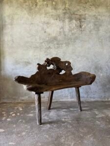 Banc en teck ancien avec design tripode et dossier ajouré, pièce artisanale unique.
