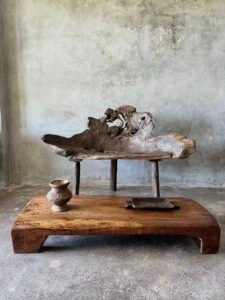 Banc en teck ancien avec design tripode et dossier ajouré, pièce artisanale unique.